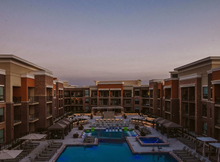 birds eye view of a large apartment complex and outdoor pool with seating